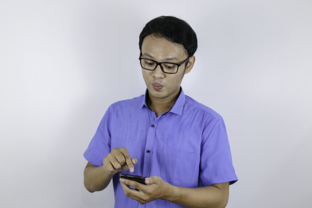 年轻的亚洲男子震惊和快乐时，他看智能手机图片下载