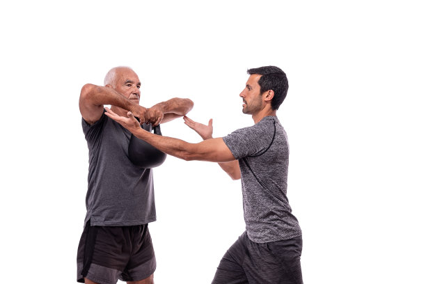 年长男性客户在健身教练指导下锻炼时，举起哑铃。在一个孤立的白色背景上。图片下载