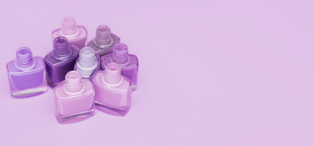 一套紫色指甲油瓶子和刷子。紫色背景上孤立的紫色指甲油组。副本的空间。图片下载