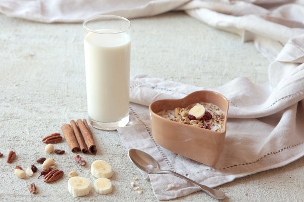 一碗有坚果、浆果、干果的自制什锦麦片，一杯牛奶和蜂蜜。健康的早餐。图片下载