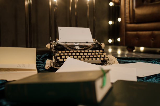 一张打字机在一张报纸上的照片，地板上有深蓝色的天鹅绒织物，里面有纸，旁边是一个棕色的皮沙发图片下载