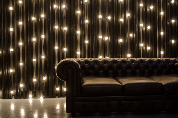 在明亮的灯光背景下，一个黑暗的房间里的皮沙发的照片图片下载