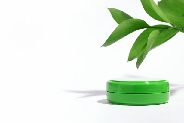 背景是装饰性的。绿色空容器与面霜保湿隔离在白色背景与植物枝和硬阴影。美容或皮肤护理概念。本空间图片下载