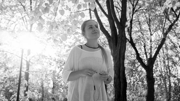 黑白照片的微笑年轻女子在体育服装与耳机在阳光公园图片下载