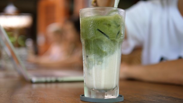 靠近金属吸管搅拌抹茶冰拿铁杏仁奶。清爽植物饮料图片下载