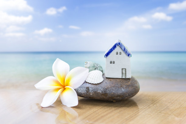 夏季海滨别墅，复古风格的陶瓷房子在石头和贝壳上与鸡蛋花在模糊的海滩背景图片下载
