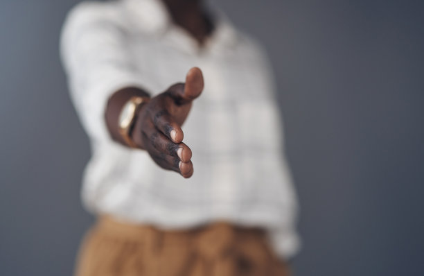 一个不知名的女商人独自站在灰色的背景下，伸出手准备握手图片下载