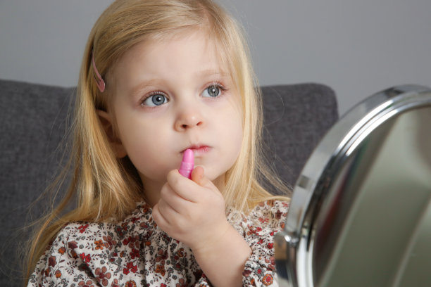 3岁的小女孩在镜子前玩化妆品图片下载