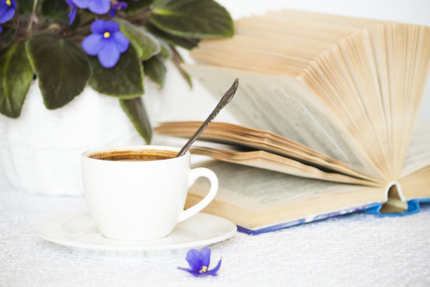 白色的桌子上放着一杯黑咖啡，打开一本书图片下载