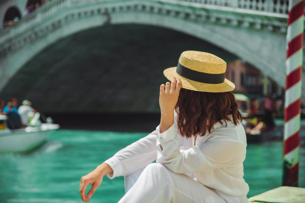 坐在意大利威尼斯里阿尔托桥附近的一名妇女坐着平底船观看大运河图片下载