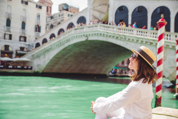坐在意大利威尼斯里阿尔托桥附近的一名妇女坐着平底船观看大运河图片下载
