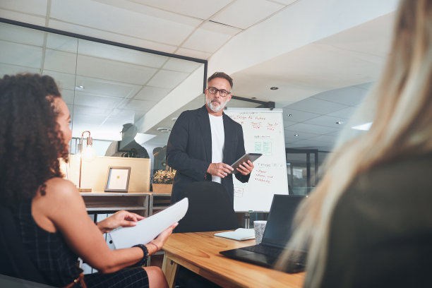 这是一位成熟的商人在一间现代办公室的会议室里使用数字平板电脑做演示的照片图片下载
