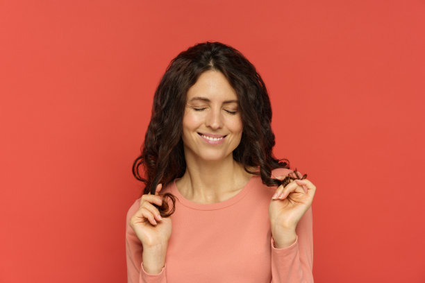 开朗的卷发女性，在新的洗发或发型处理后，触摸自然健康的卷发图片下载