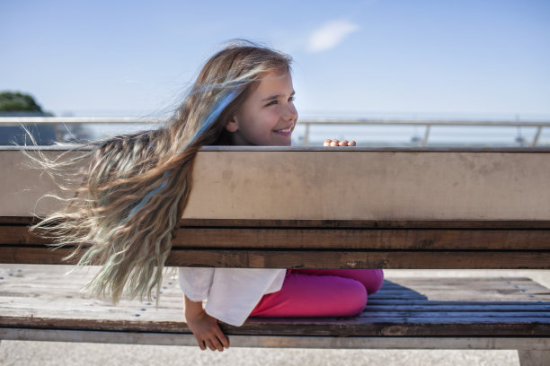 深色头发的青春期前女孩与蓝色高光看着桥上的河流，侧视图，夏天的一天图片下载