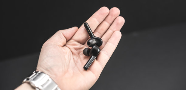 一只手拿着黑色背景上的空白无线蓝牙耳机图片下载