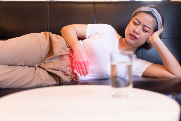 亚洲女性胃痛，女性腹痛，经期痉挛或经前综合症躺在沙发上图片下载
