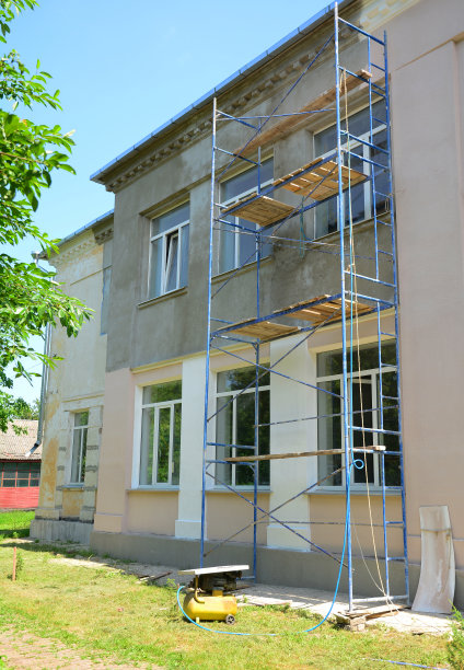 在房屋装修期间，从脚手架上抹灰、渲染、脱脂涂层和粉刷外墙。图片下载