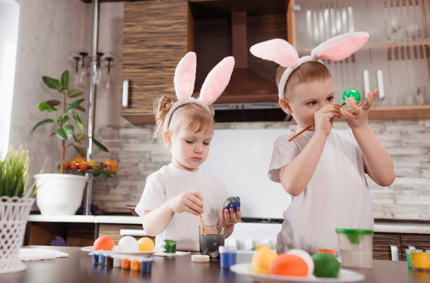 复活节快乐。有趣的小朋友们带着兔耳朵玩耍，准备过节和画彩蛋。图片下载