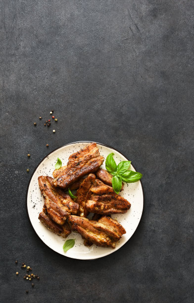 野餐用的烧烤猪肉。烤排骨盘和酱汁放在石黑色的桌子上。从以上观点。图片下载