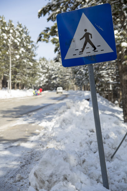 雪牌，雪牌在被雪覆盖的街道上的行人过马路的标志，并被清除以便汽车通过图片下载