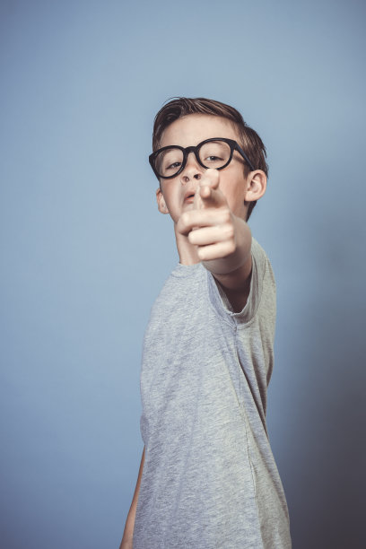 带着厚厚的黑眼镜在蓝色背景下摆姿势的酷男孩图片下载