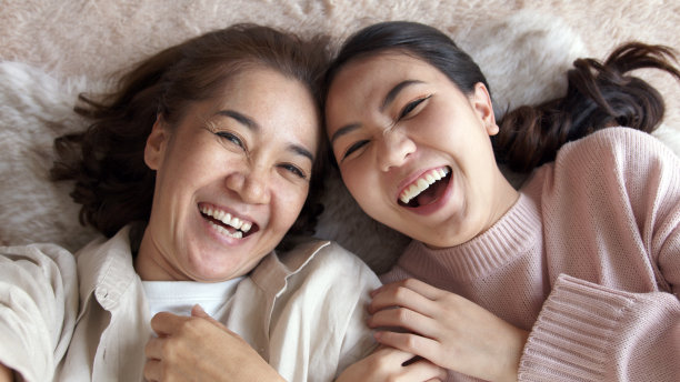 POV迷人的美丽的两人亚洲小姐女孩用手机拍照照片视频喜出天外躺在家里的地板上度过美好的日子一起隔离在妈妈的健康保健。图片下载