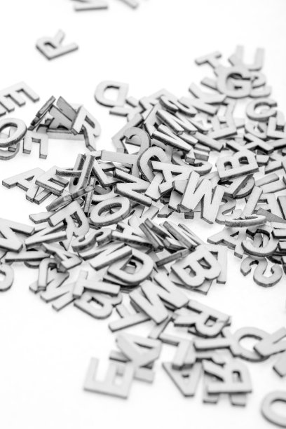 用激光切割机从薄胶合板上剪下的小木字，随机地堆在白色的背景上。黑与白的照片。图片下载