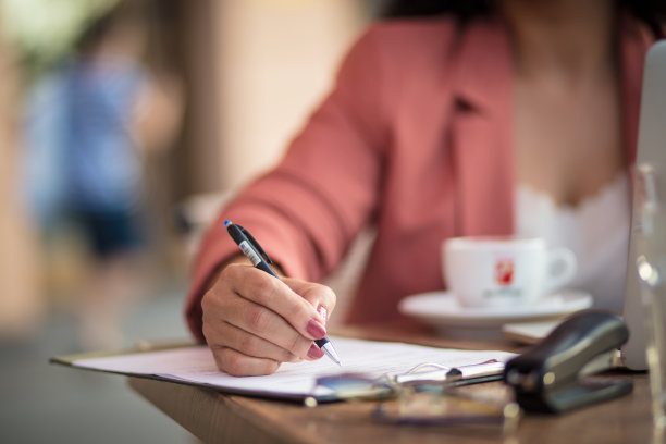 商务女性坐在café写文件。专注在手边。图片下载