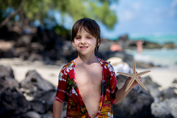 孩子与海星嬉戏，孩子快乐沙滩夏日概念图片下载