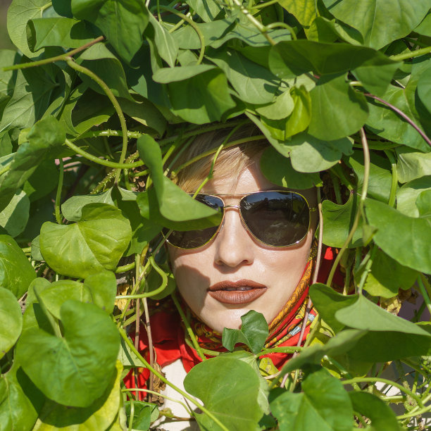 美丽的白色女孩与绿色的叶子周围的脸图片下载