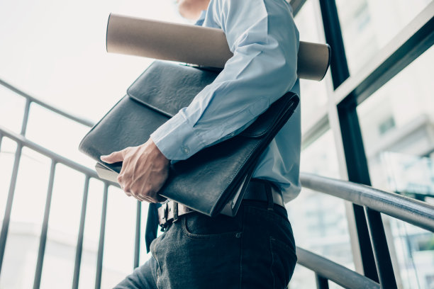 忙碌的商人手里拿着卷宗和图纸。忙碌或有很多工作要做，男人强调工作观念。图片下载