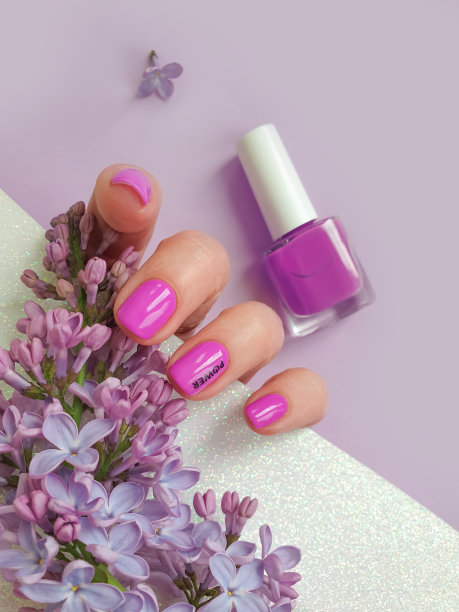 女性手美丽的美甲在一个彩色的背景花紫丁香图片下载
