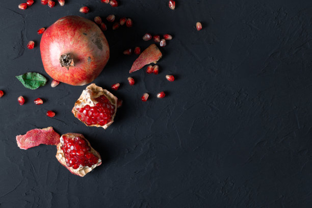 成熟的红石榴，鲜嫩多汁的种子在一个黑色的背景。天然维生素。健康食品的概念。食品的背景。平铺与拷贝空间。图片下载