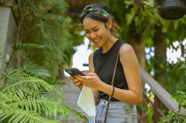 年轻女子很高兴当她检查智能手机，微笑和快乐的概念图片下载