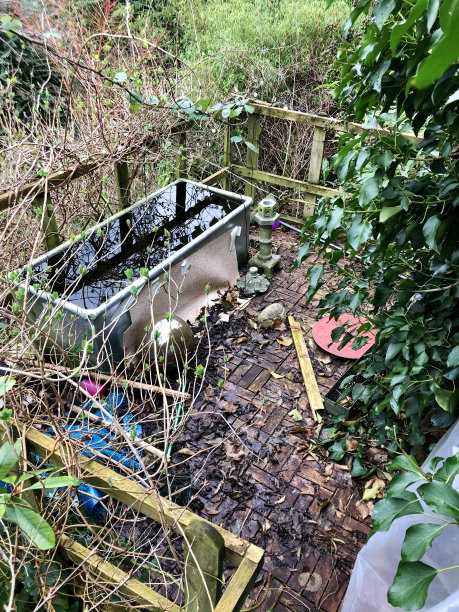 凌乱的花园树屋露台露台阳台在冬季结束，落叶在柚木装饰瓷砖的壁画用餐区，昏暗的锌槽池，花园春季清洁概念图片下载