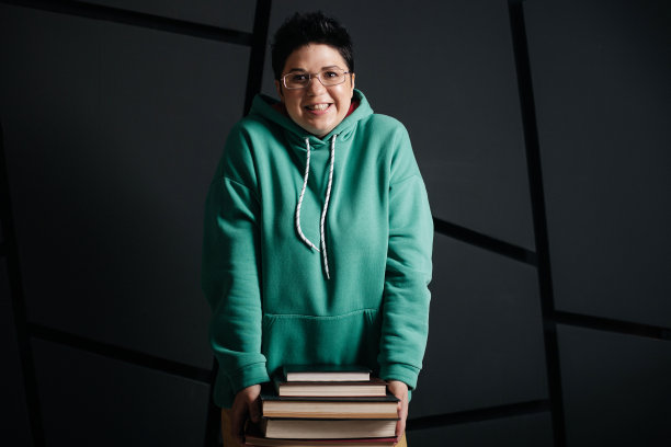 黑发短发的女孩戴着眼镜，带着书，背景是黑色的图片下载