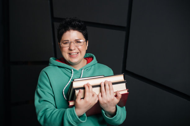 黑发短发的女孩戴着眼镜，带着书，背景是黑色的图片下载