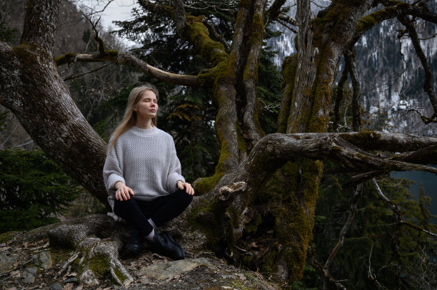 在阿布哈兹的里察湖畔，女孩坐在一棵树上冥想图片下载