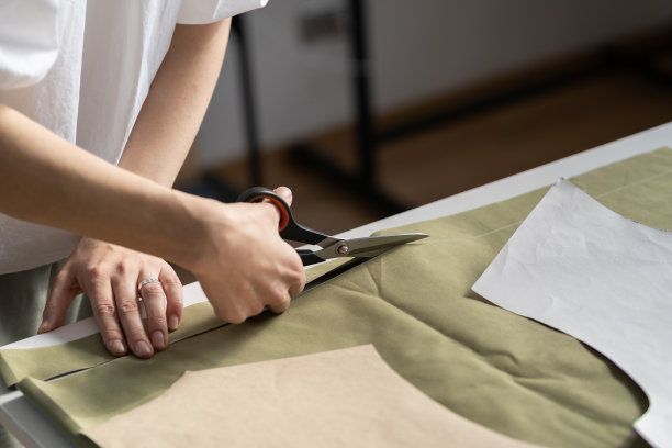 裁缝在裁缝车间裁剪图案:设计师的妇女手用剪刀裁剪织物的特写图片下载