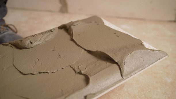 大师用胶水涂瓷砖。师傅把黏液涂在大理石瓷砖上。图片下载