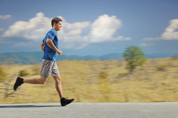 一个穿着运动服的家伙在乡间的柏油路上跑步图片下载