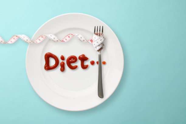 用番茄酱在盘子上写的减肥信，用带卷尺的叉子在浅蓝色的背景上图片下载