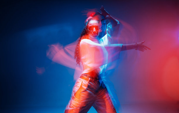 酷混合种族的年轻女孩移动在多彩的工作室灯光。长时间的曝光。当代时尚广告照片图片下载