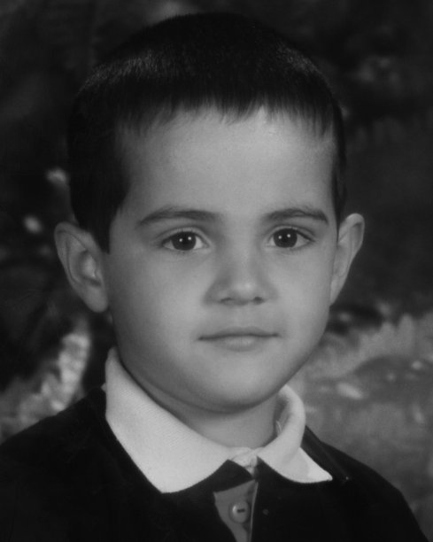 微笑沉思的小男孩看着相机图片下载