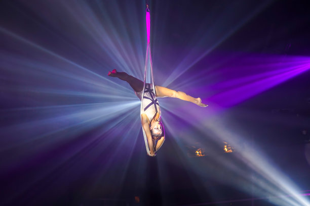 柔韧的女子体操运动员倒立在肩带上做倒立。图片下载