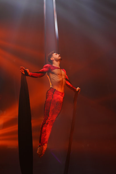 巴西强壮性感的空中杂技演员做平衡运动在空中丝绸在红灯。图片下载