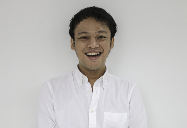 年轻有趣的亚洲人的肖像与白衬衫看相机和微笑快乐的表情图片下载