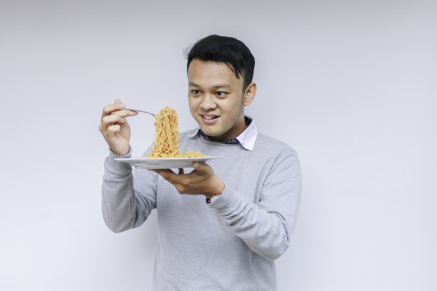 快乐的年轻亚洲男子享受面条肖像。吃午饭的概念。图片下载