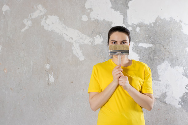 一个穿着黄色鲜艳t恤的女修理工拿着一把刷子。文本。全包维修图片下载