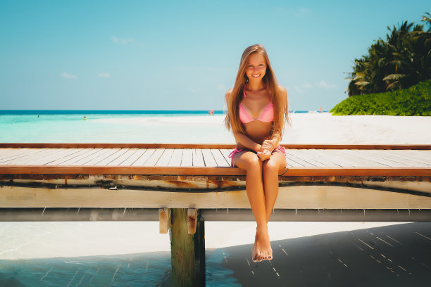 年轻的金发女孩坐在泻湖的码头上图片下载